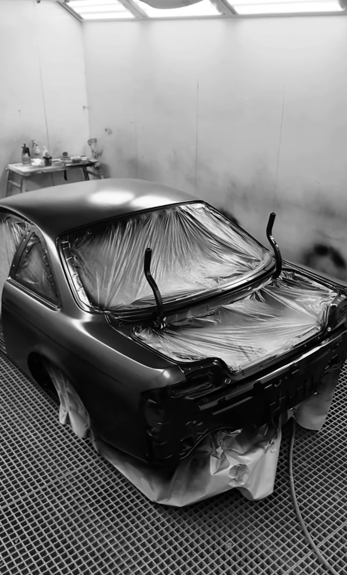 Coupe rear quarter in the spray booth, fresh basecoat
