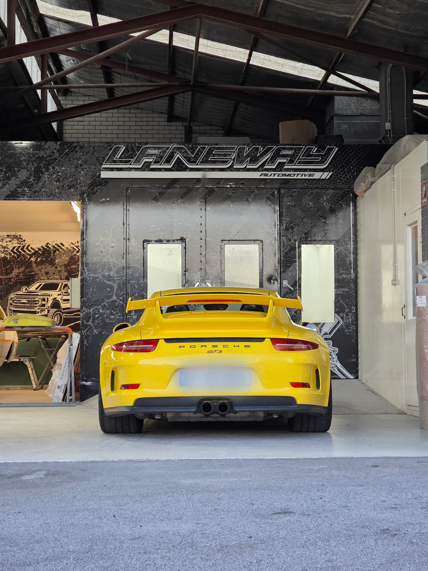 Yellow Porsche 911 GT3 parked against the Laneway wall